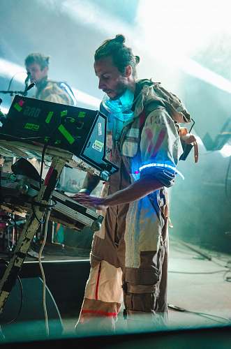 human man in brown overalls in front of computer musician